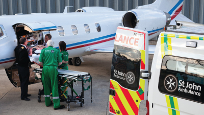 Paramedics load a patient on a stretcher into a small plane