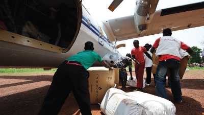 Humanitarian workers help offload cargo from a plane.